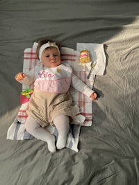 a baby doll laying on a bed with a blanket