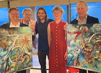 a group of people posing for a picture holding paintings